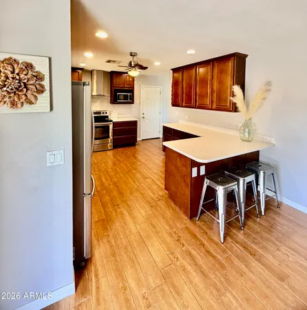 a living room with stainless steel appliances kitchen island granite countertop a stove and a wooden floor