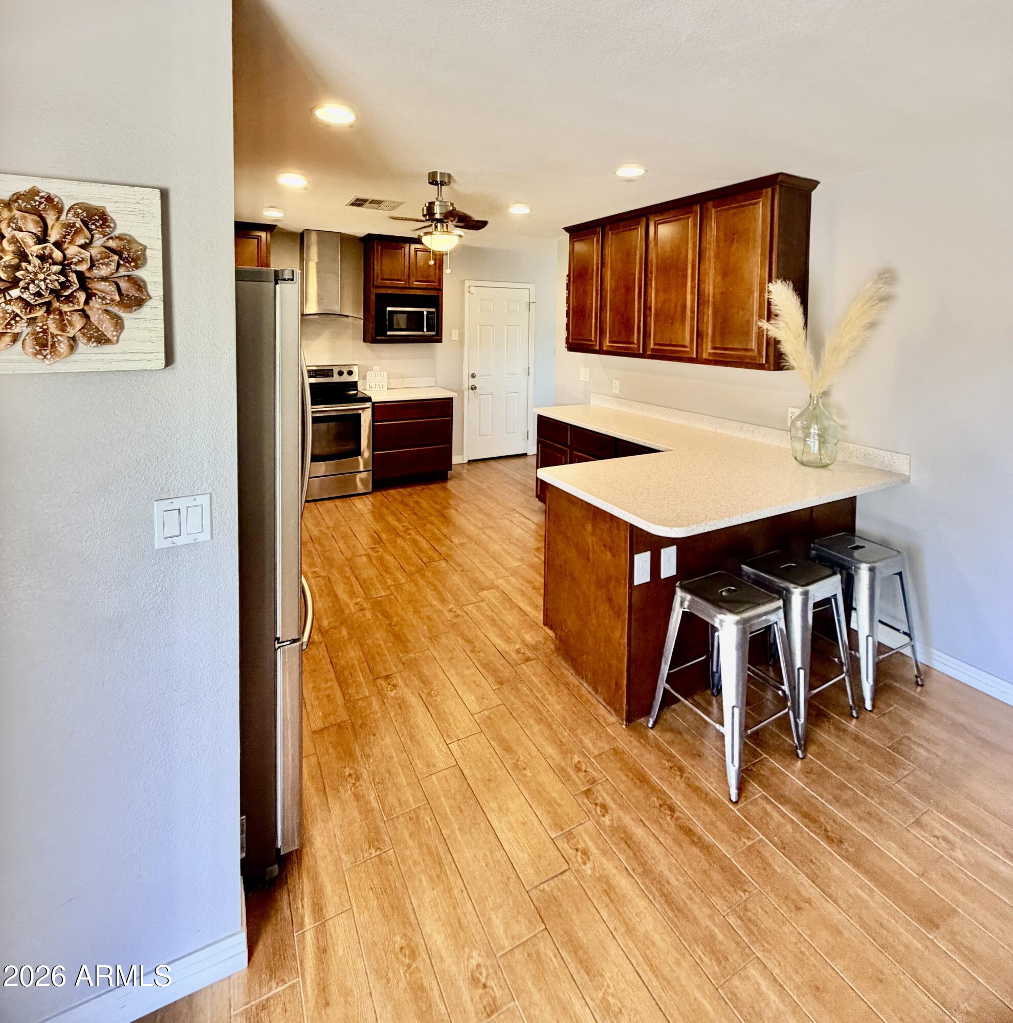 1601 West Lamar Road Phoenix, AZ 85015 - Photo 9 of 28 a living room with stainless steel appliances kitchen island granite countertop a stove and a wooden floor