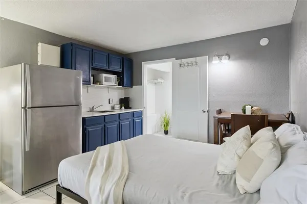 a bedroom with a bed and a refrigerator