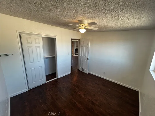 an empty room with wooden floor cabinet and ceiling fan