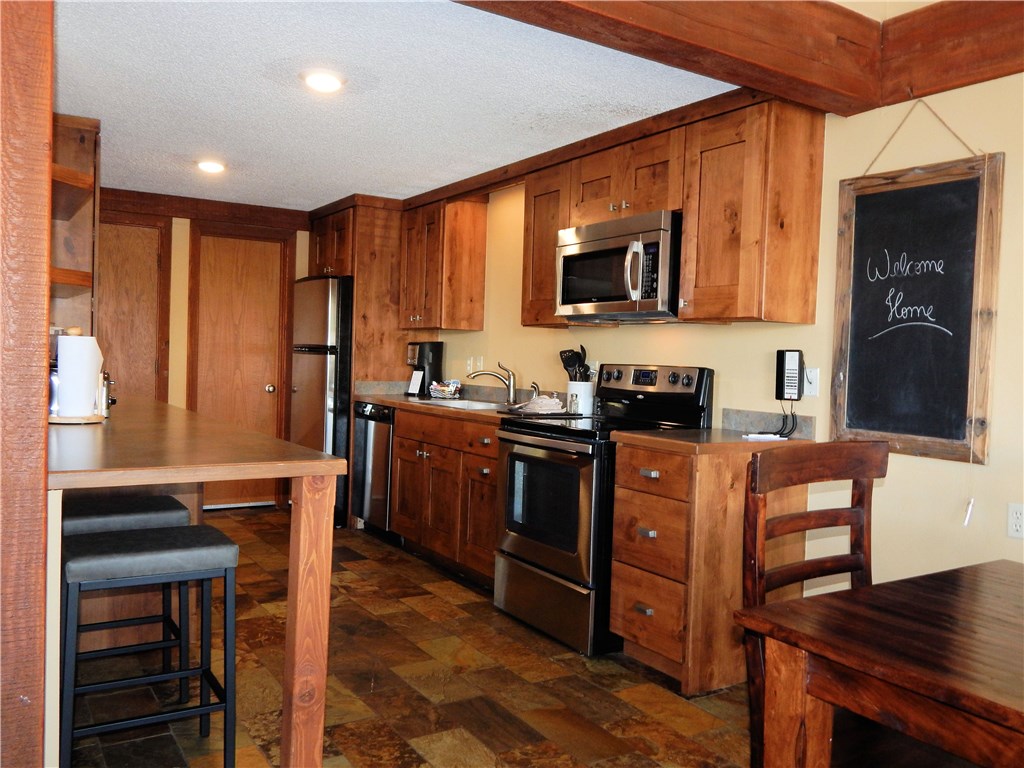 57 Fuller Placer Road, Unit 1B Breckenridge, CO 80424 - Photo 5 of 19 a kitchen with stainless steel appliances granite countertop wooden cabinets a stove top oven a sink and dishwasher