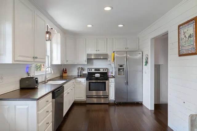 a kitchen with granite countertop white cabinets white stainless steel appliances and sink