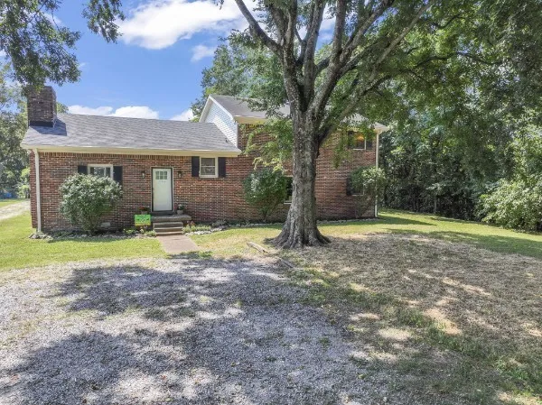 a view of a house with a yard and large tree