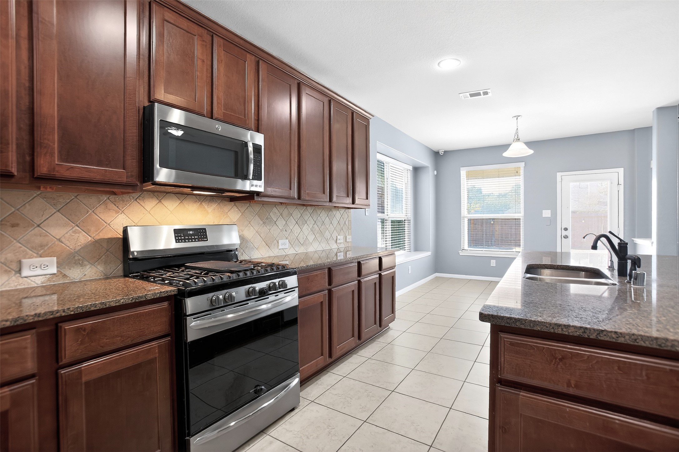 25315 Terrain Park Drive Spring, TX 77373 - Photo 9 of 47 a kitchen with stainless steel appliances granite countertop a stove microwave and sink