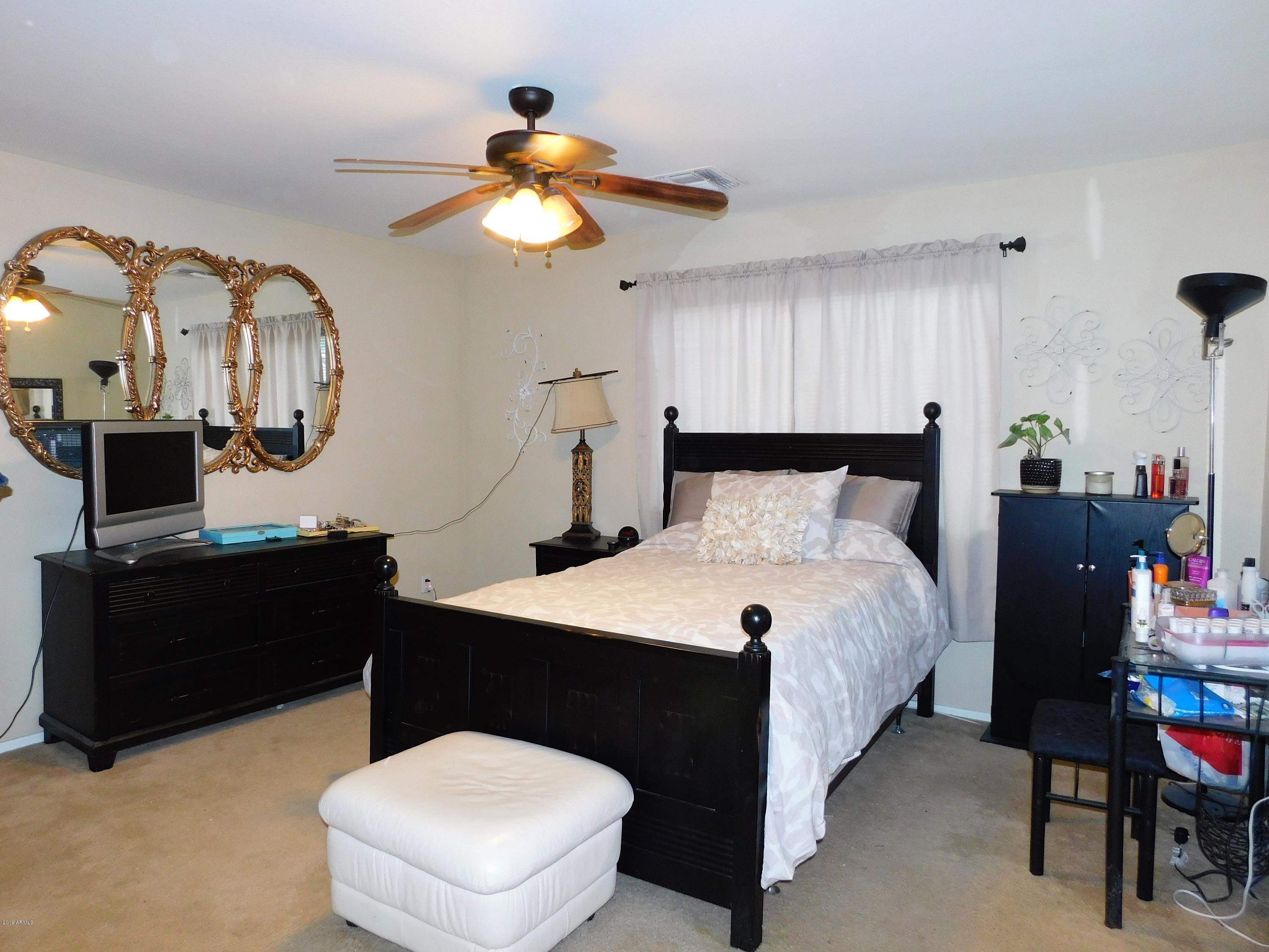 15814 West Jackson Street Goodyear, AZ 85338 - Photo 16 of 18 a bedroom with a bed and a chandelier