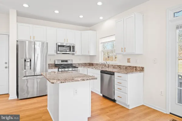 a kitchen with stainless steel appliances granite countertop a stove top oven a sink and a refrigerator