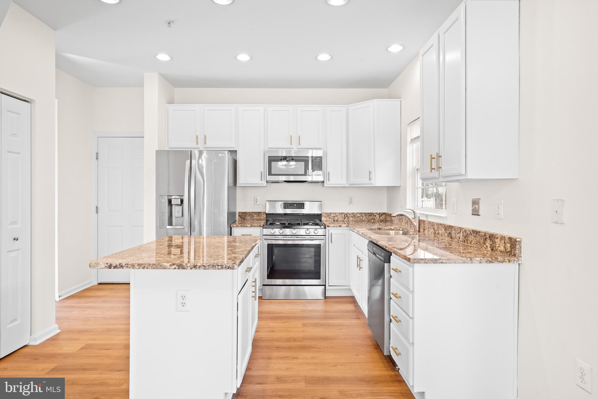 9602 Stuart Lane Clinton, MD 20735 - Photo 15 of 40 a kitchen with stainless steel appliances granite countertop a stove top oven a sink and a refrigerator