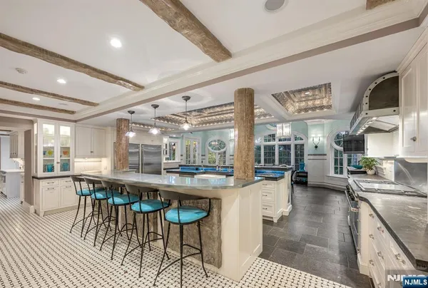 a large dining hall with stainless steel appliances granite countertop a stove oven a dining table and chairs with wooden floor