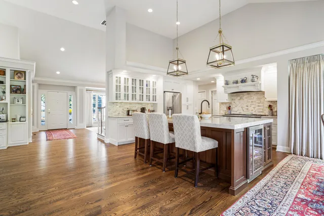 a kitchen with stainless steel appliances granite countertop a refrigerator a sink dishwasher a stove and a dining table with wooden floor