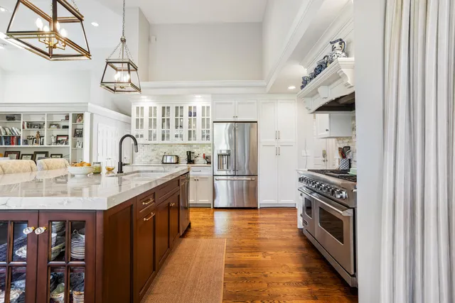 a view of a kitchen with kitchen island a large window cabinets a sink and stainless steel appliances