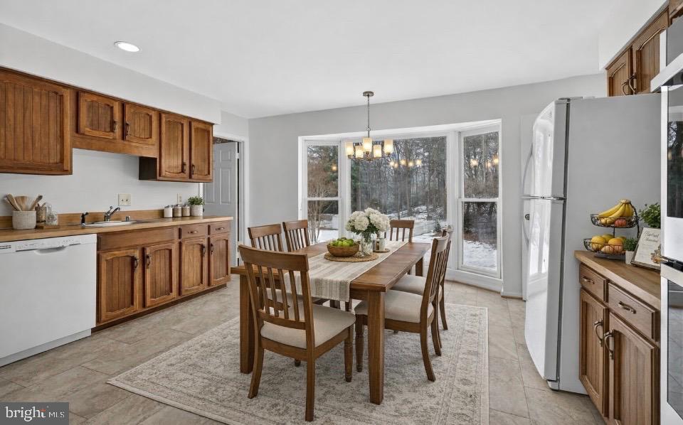 15200 Winstead Lane Silver Spring, MD 20905 - Photo 23 of 53 a dining room with stainless steel appliances granite countertop a stove a refrigerator a sink dishwasher a dining table and chairs with wooden floor