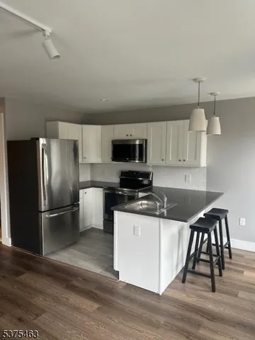 a kitchen with granite countertop a refrigerator and a stove top oven