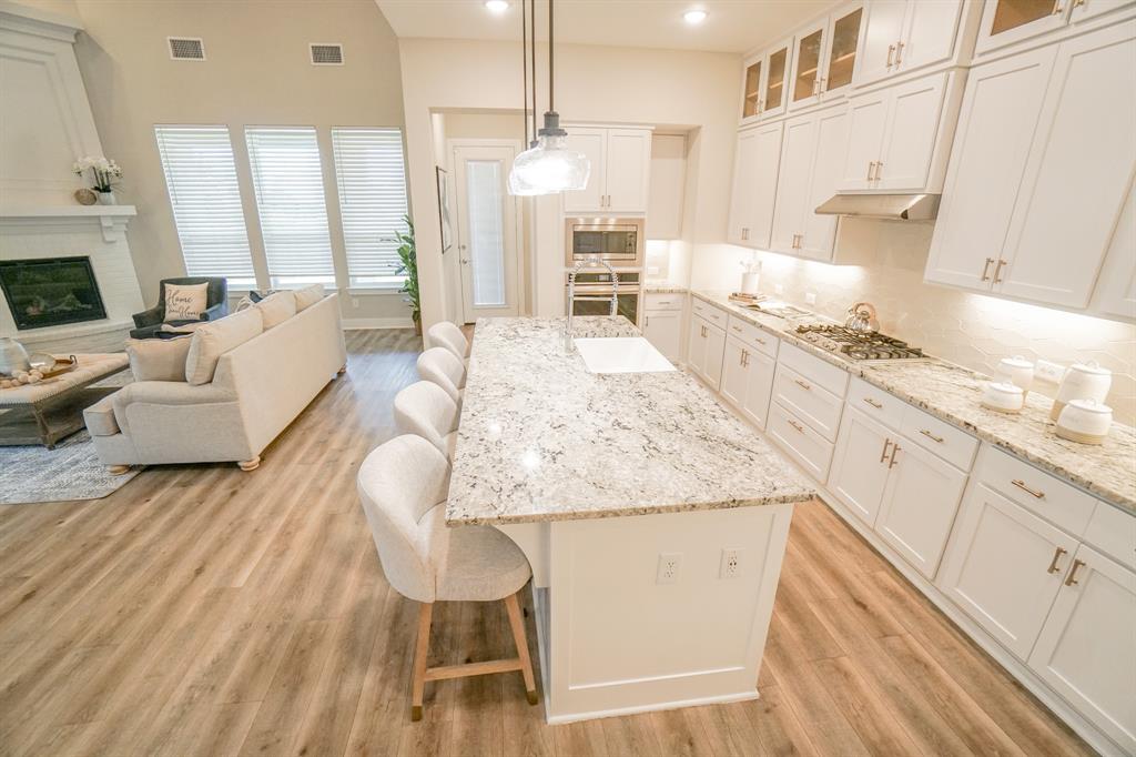 1309 Old Rocksprings Pass Mansfield, TX 76063 - Photo 7 of 36 Kitchen featuring a large island with seating, white shaker-style cabinetry, stainless steel appliances, and light-colored countertops