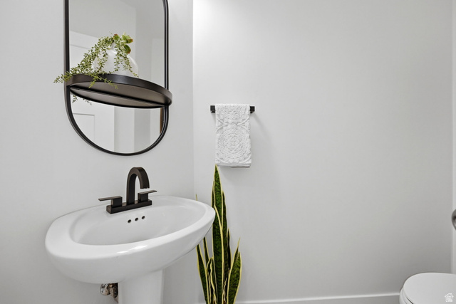 57 McCall Ln. Farmington, UT 84025 - Photo 15 of 36 Pedestal sink with a matte black faucet and coordinating oval mirror featuring an integrated shelf