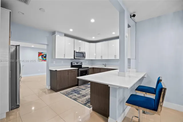 a kitchen with stainless steel appliances kitchen island granite countertop a sink refrigerator and cabinets