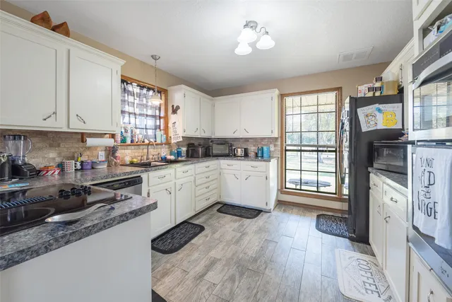 a kitchen with stainless steel appliances white cabinets a stove a sink and a window