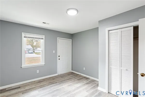 a view of an empty room with window and wooden floor