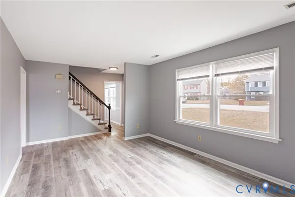 a view of an empty room with wooden floor and a window