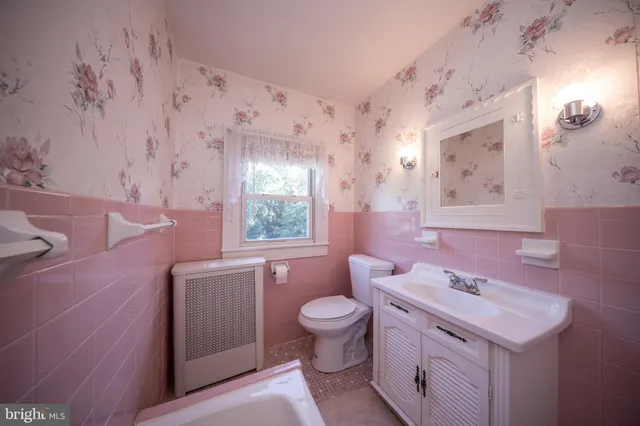 a bathroom with a sink a toilet a window and a mirror