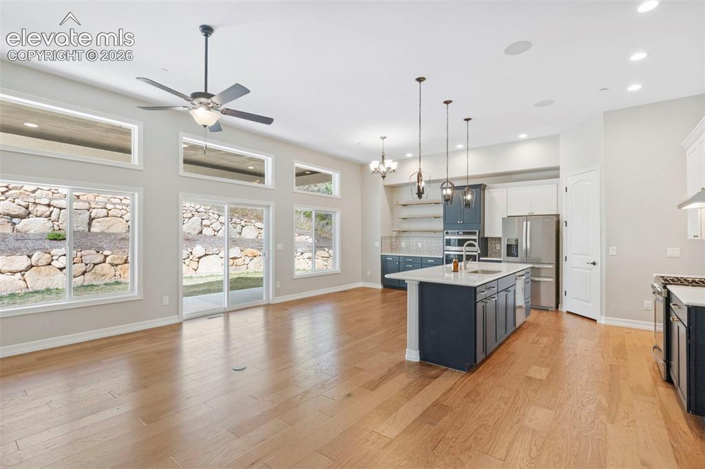 5375 Old Star Ranch View Colorado Springs, CO 80906 - Photo 12 of 47 Spacious open-concept living area featuring wood-finish flooring, a contemporary ceiling fan, and extensive natural light from multiple windows and a sliding glass door