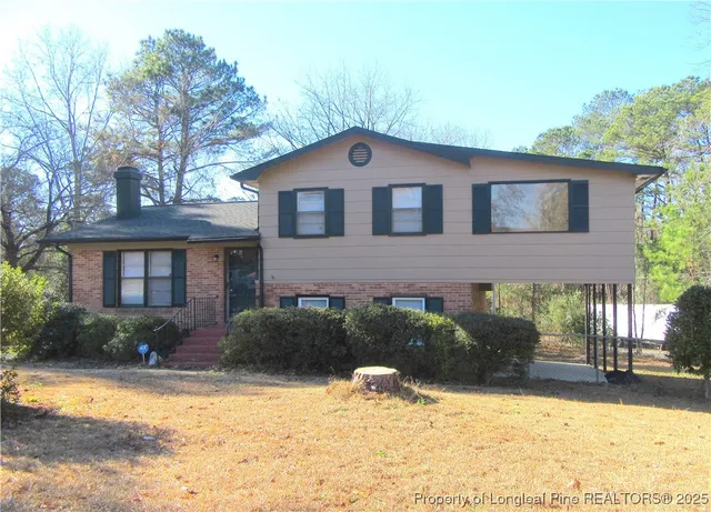 a brick house with a yard plants and large tree
