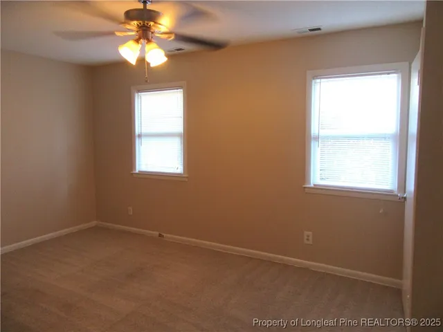 an empty room with windows and fan