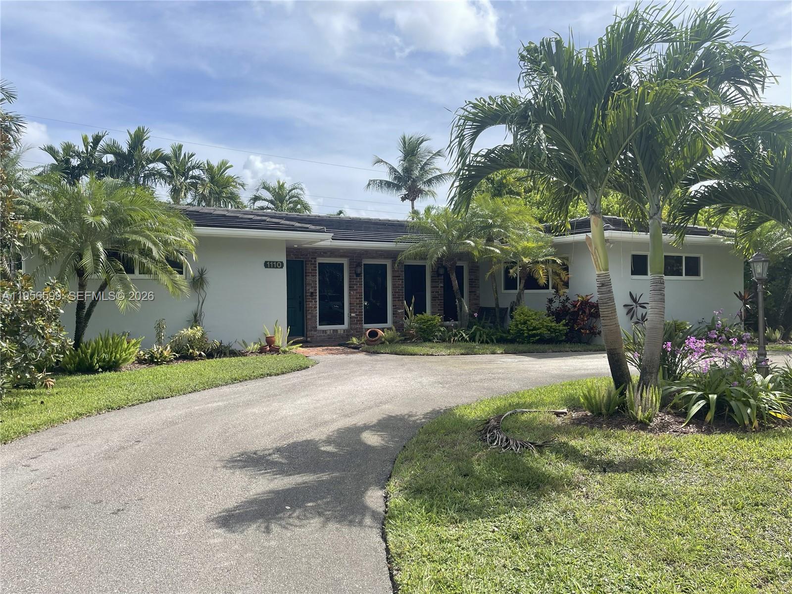 1110 Redbird Avenue Miami Springs, FL 33166 - Photo 2 of 25 a front view of a house with a yard and a garage