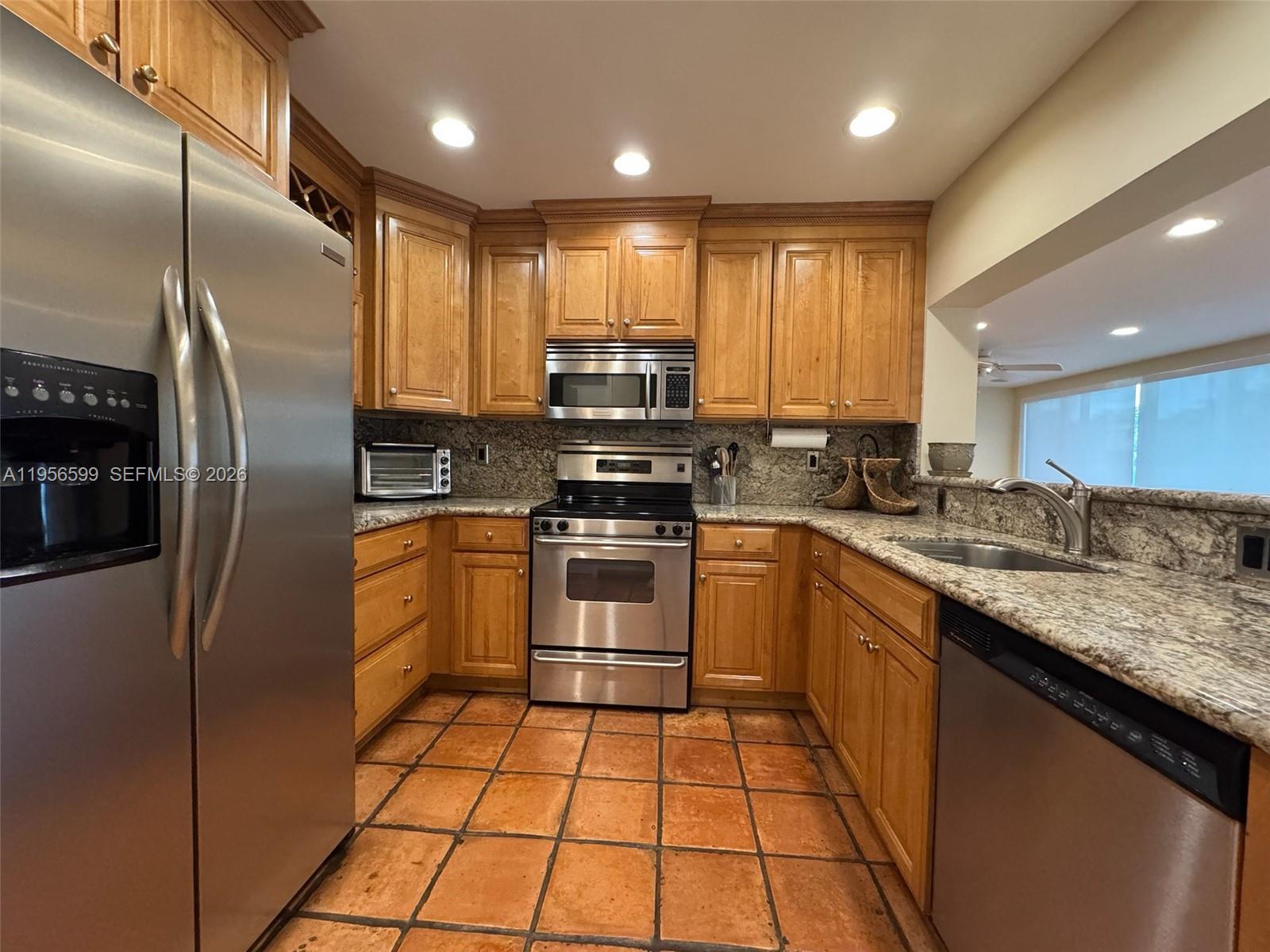 1110 Redbird Avenue Miami Springs, FL 33166 - Photo 23 of 25 a kitchen with stainless steel appliances granite countertop a stove a sink and a refrigerator