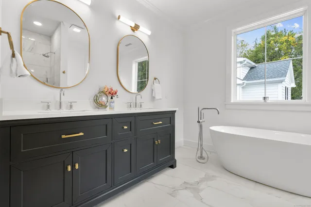 a bathroom with a double vanity sink a mirror and a bathtub next to a window
