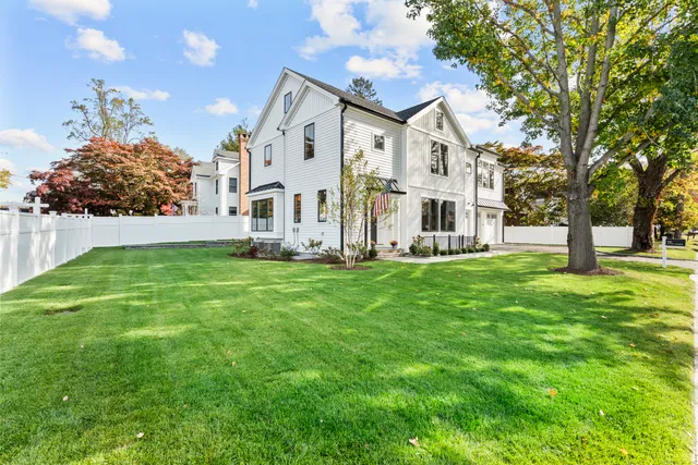 a view of a white house with a big yard and large trees
