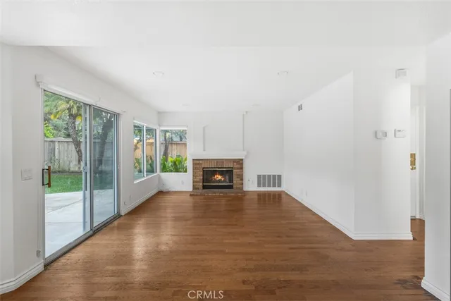 a view of a livingroom with wooden floor a fireplace and window