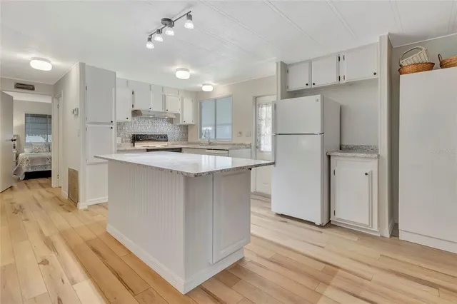 a kitchen with kitchen island white cabinets and refrigerator