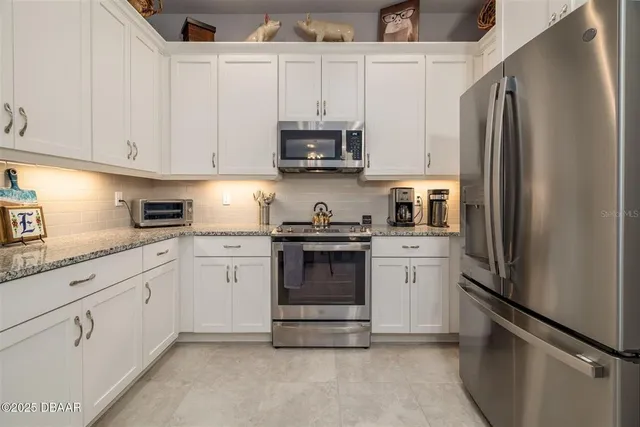 a view of a kitchen with kitchen island white cabinets and stainless steel appliances
