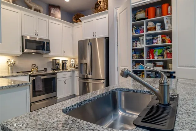 a kitchen with stainless steel appliances granite countertop a refrigerator stove and white cabinets