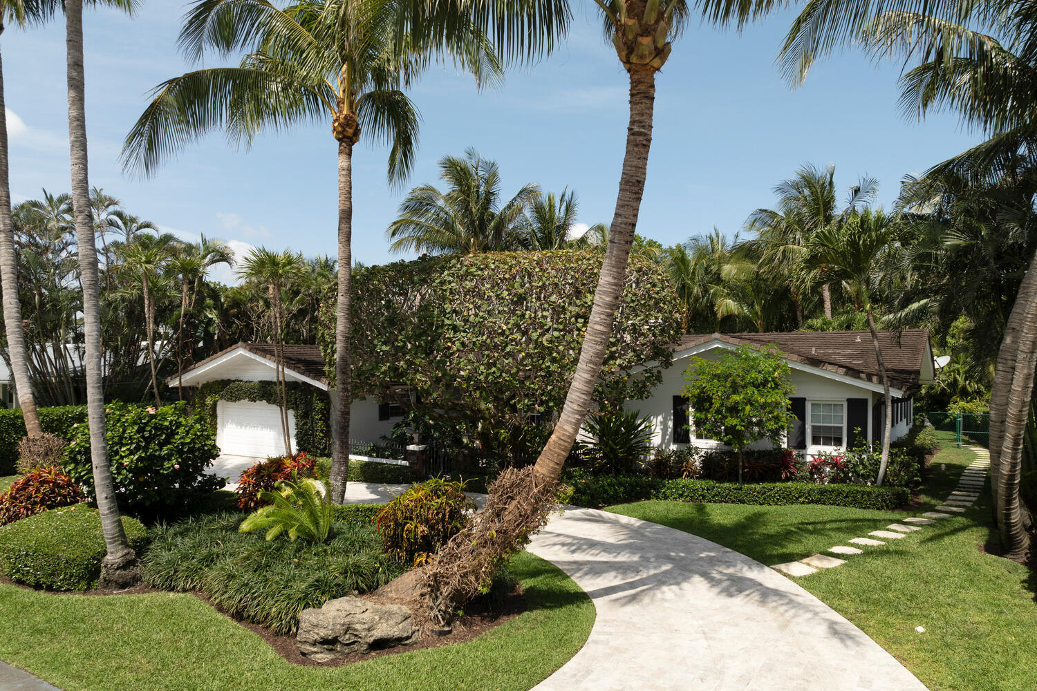 a front view of a house with a yard and palm trees