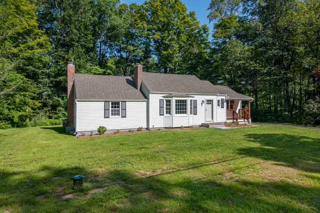 a aerial view of a white house sitting in big yard with large trees