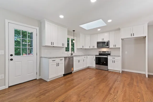 a kitchen with white cabinets stainless steel appliances and window