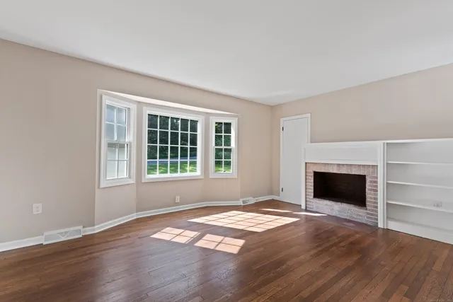 a view of empty room with wooden floor and fireplace