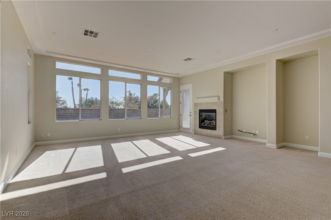 6383 Radiant Rapture Avenue Las Vegas, NV 89131 - Photo 5 of 17 Unfurnished living room with a tiled fireplace, carpet flooring, and crown molding
