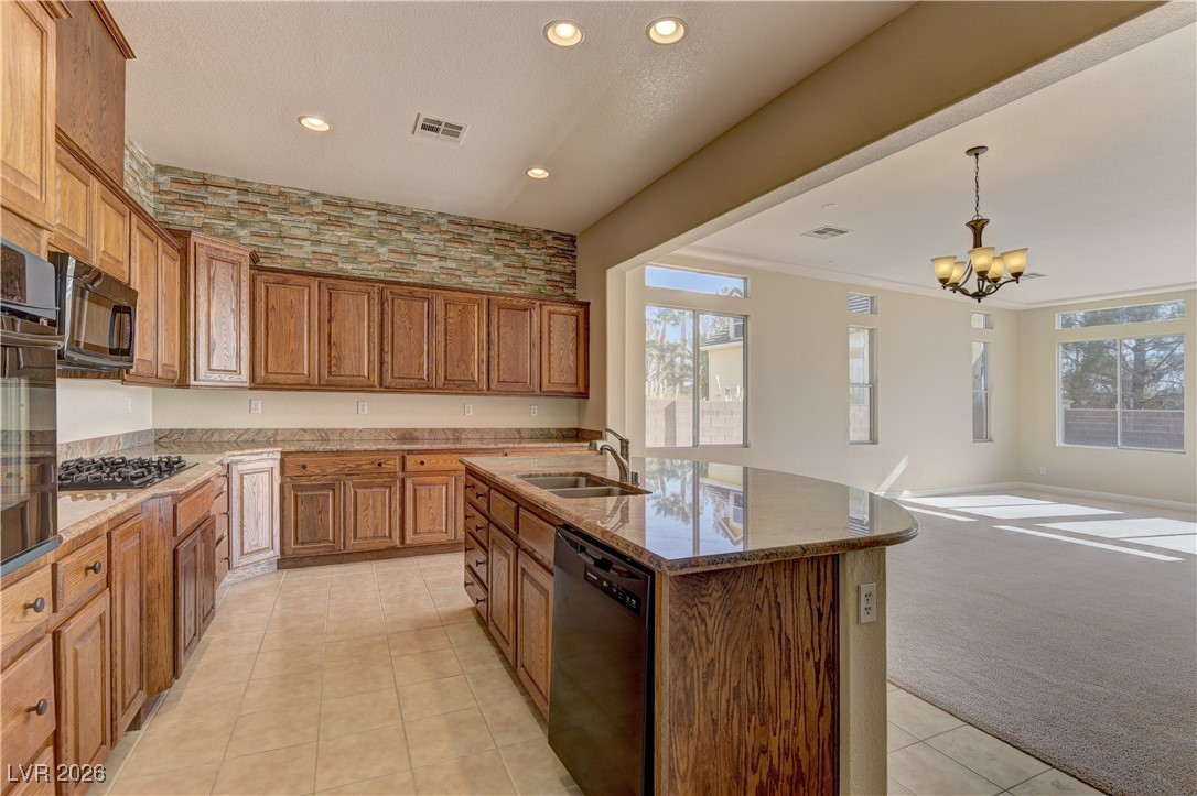 6383 Radiant Rapture Avenue Las Vegas, NV 89131 - Photo 7 of 17 Kitchen featuring light carpet, brown cabinetry, black appliances, a center island with sink, and decorative light fixtures