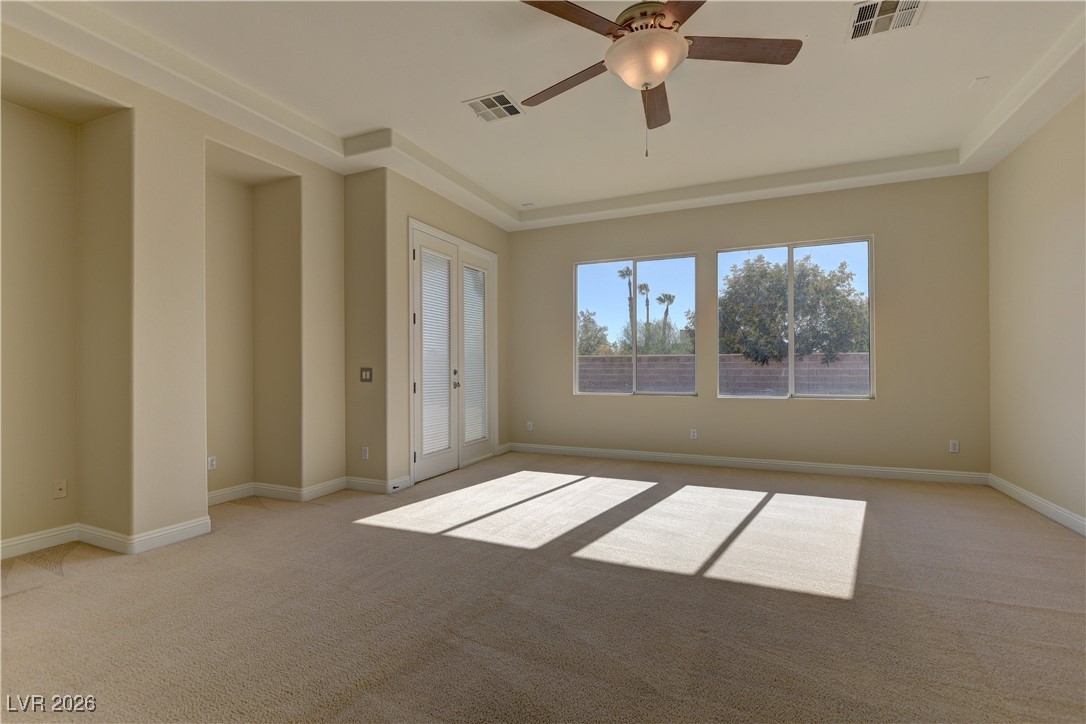6383 Radiant Rapture Avenue Las Vegas, NV 89131 - Photo 9 of 17 Empty room with french doors, light colored carpet, a ceiling fan, and a raised ceiling