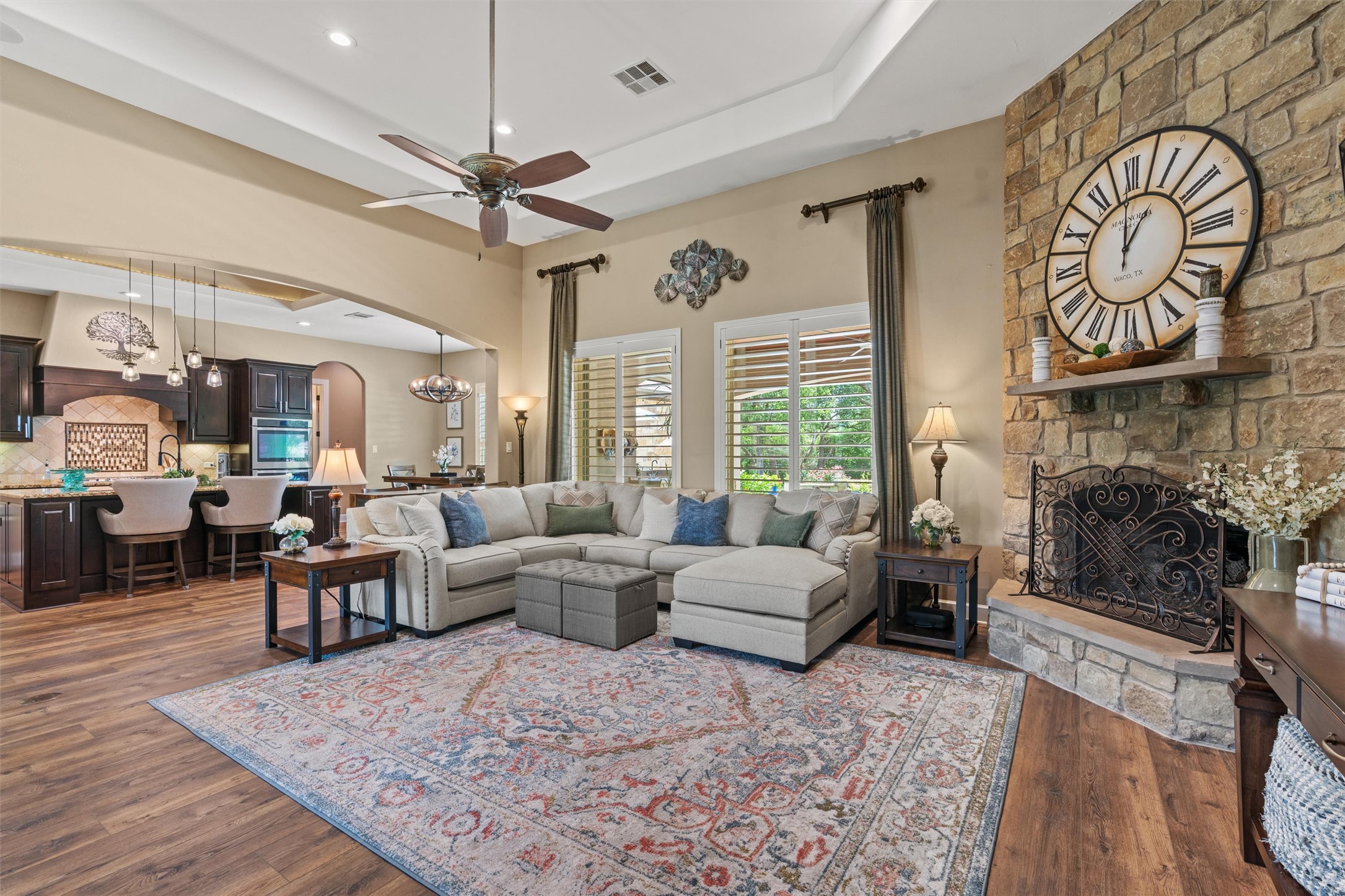 104 Adobe Cove Georgetown, TX 78633 - Photo 7 of 39 Living area with a tray ceiling, arched walkways, ceiling fan, a chandelier, and a stone fireplace