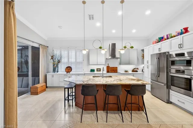 a kitchen with stainless steel appliances granite countertop a sink a stove a refrigerator and chairs