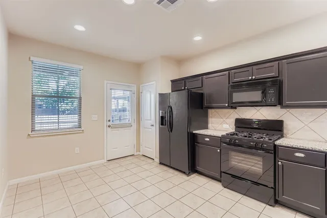 a kitchen with granite countertop a refrigerator and a stove top oven