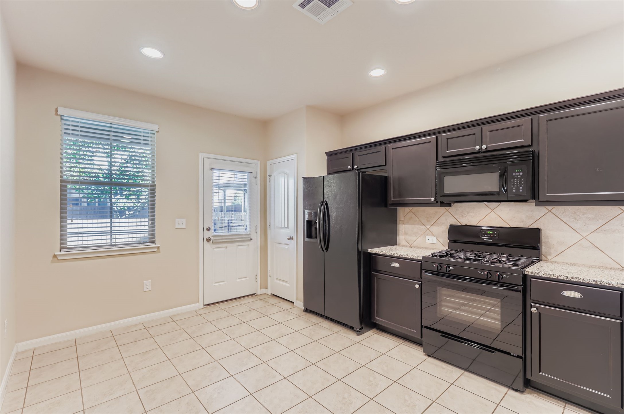 2880 Donnell Drive, Unit 803 Round Rock, TX 78664 - Photo 3 of 11 a kitchen with granite countertop a refrigerator and a stove top oven