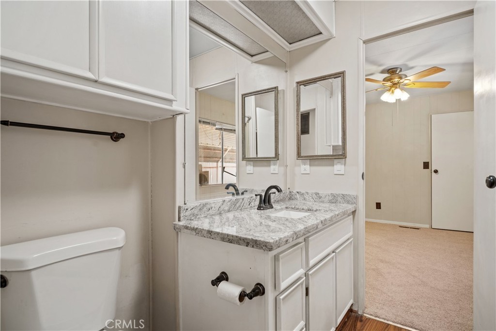 13393 Mariposa Road, Unit 169 Victorville, CA 92395 - Photo 17 of 36 a bathroom with a granite countertop sink a toilet and mirror