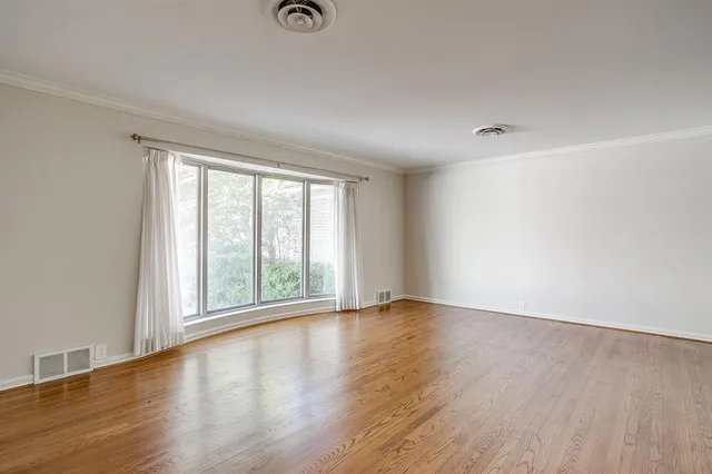 a view of an empty room with wooden floor and windows