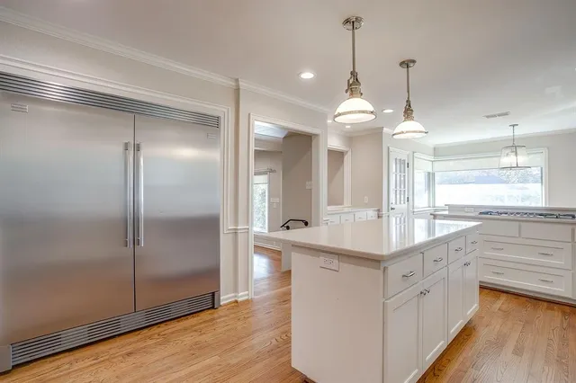 a large kitchen with cabinets wooden floor and stainless steel appliances