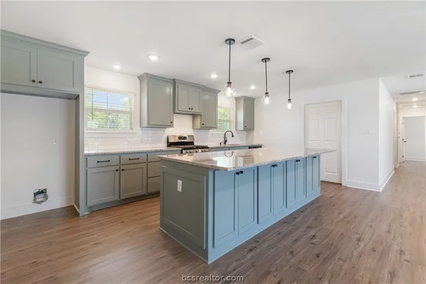 a kitchen with kitchen island a sink a center island stainless steel appliances and a window