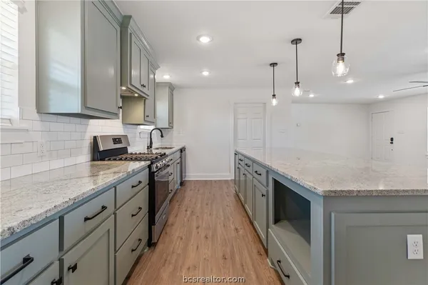 a large kitchen with stainless steel appliances granite countertop a sink a stove and a wooden floors